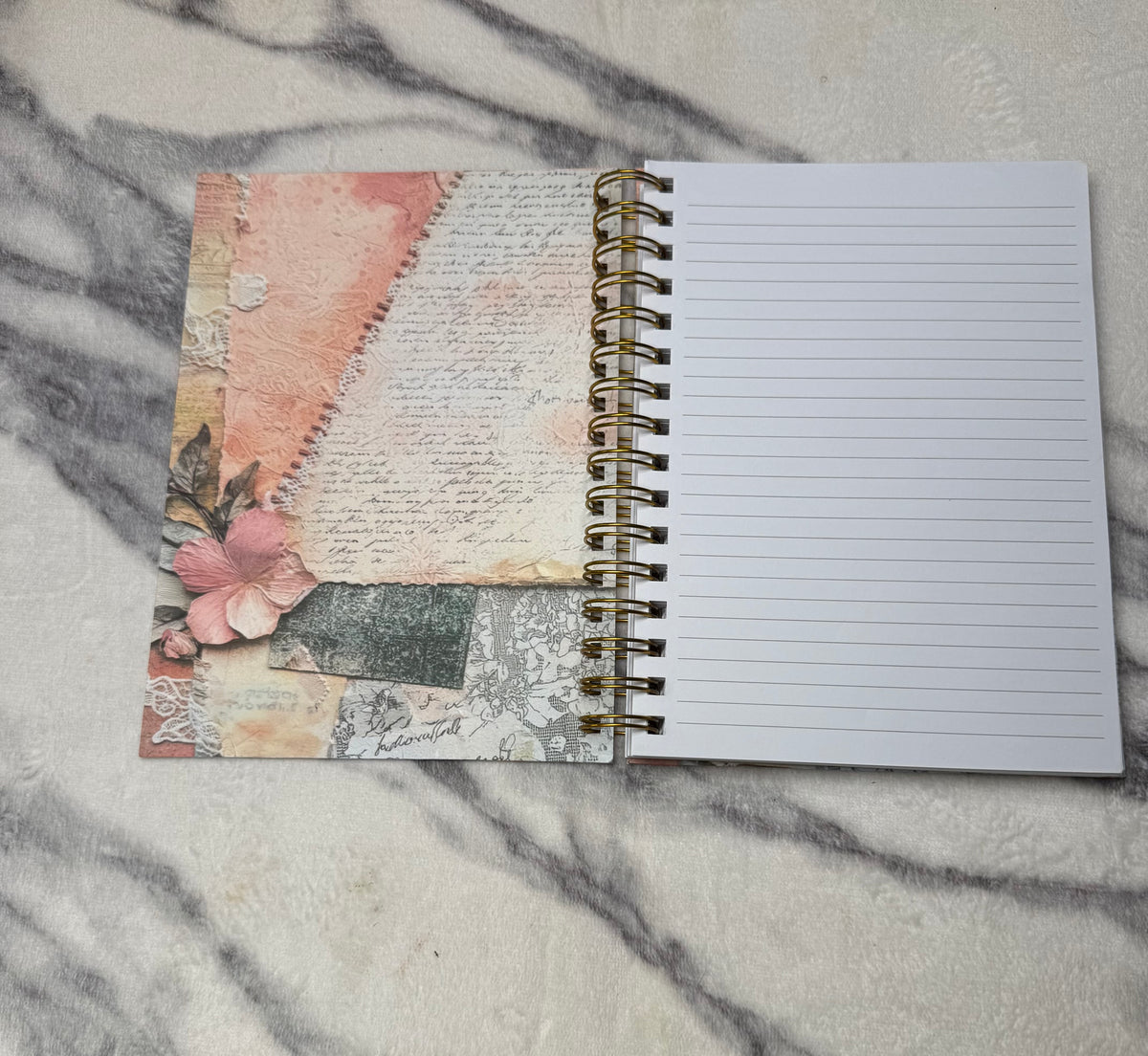 Open journal: Open lined spiral journal showing a pink floral inside cover and a ruled writing page.