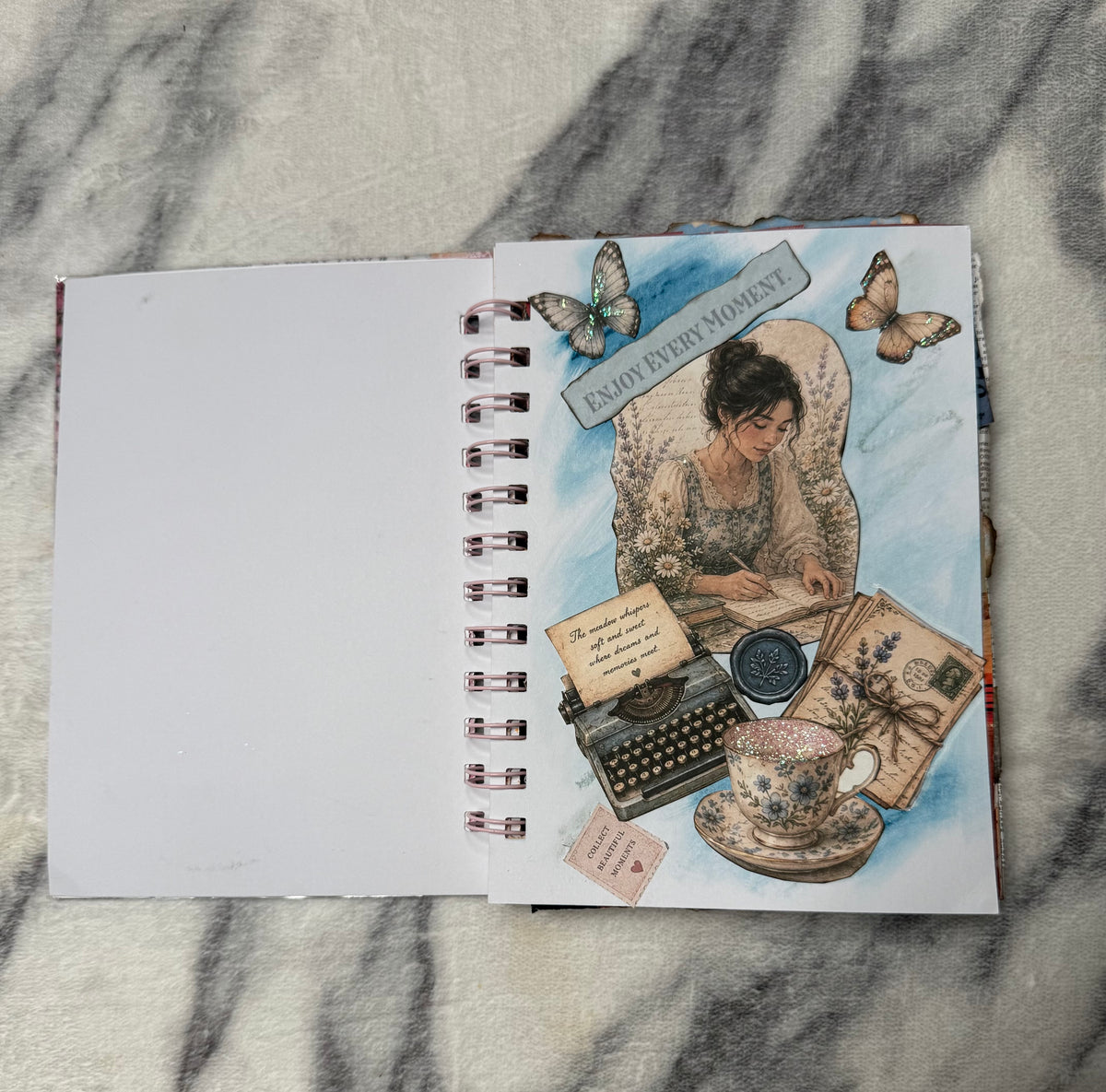 Blue collage page: “Mini junk journal collage page with butterflies, a vintage typewriter, teacup, and ‘Enjoy every moment’ lettering.”